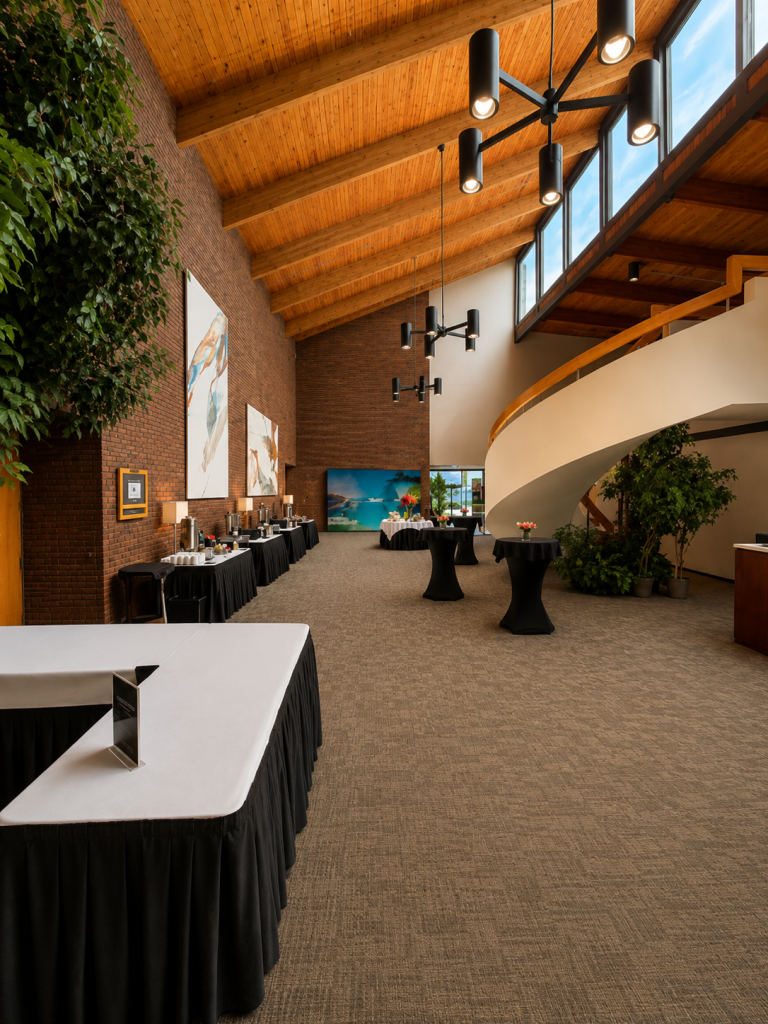 A view of the lobby featuring the spiraled staircase up to the mezzanine and some round standing tables.